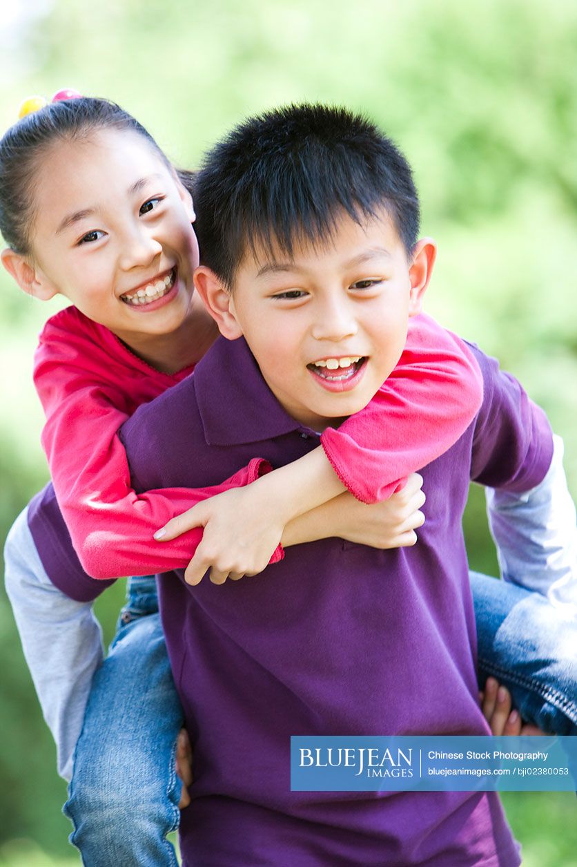 Young girl carrying sister giving piggyback ride Stock Photo