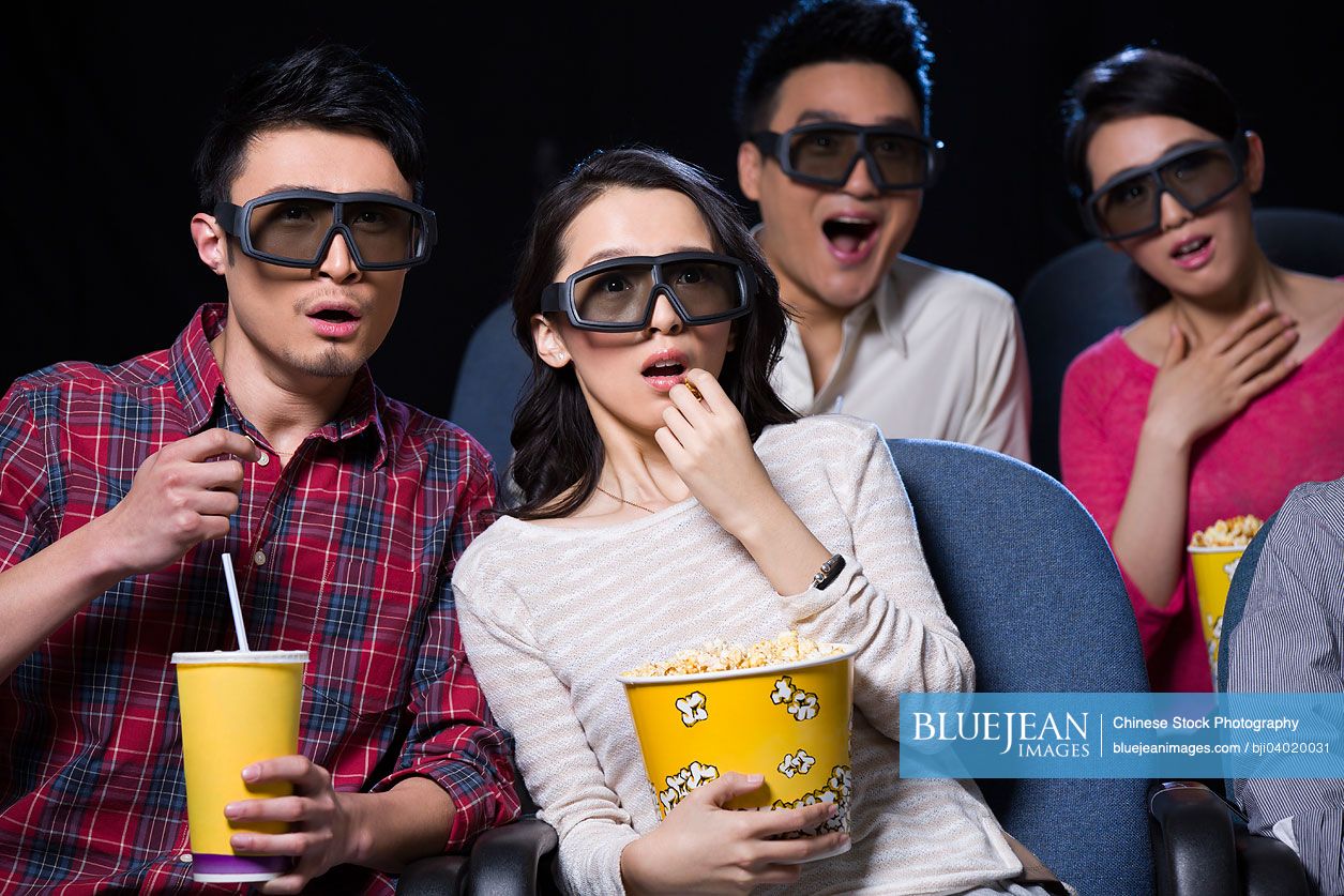 Young Chinese couple watching 3D movie in cinema