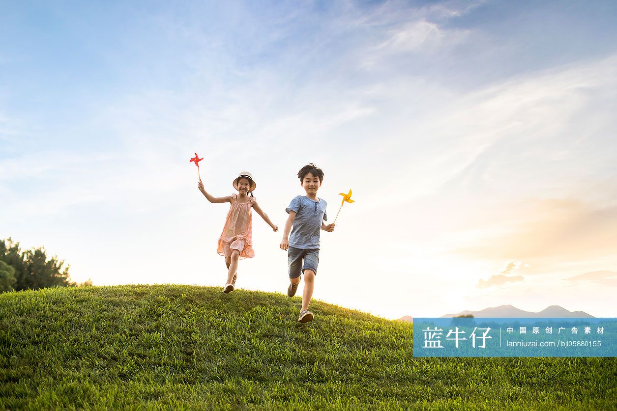 姐弟俩在草地上玩风车玩具