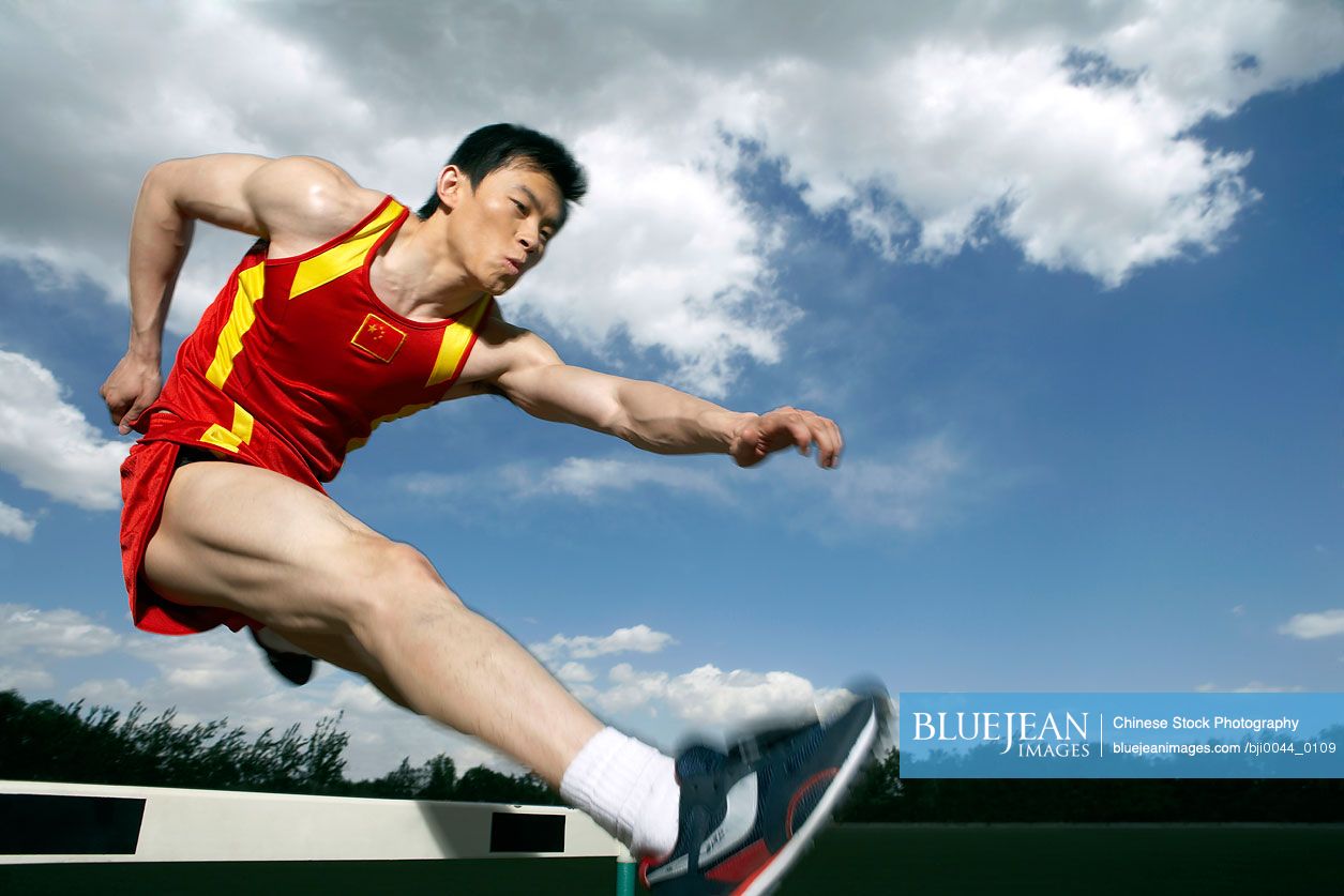 Chinese athlete jumping over a hurdle