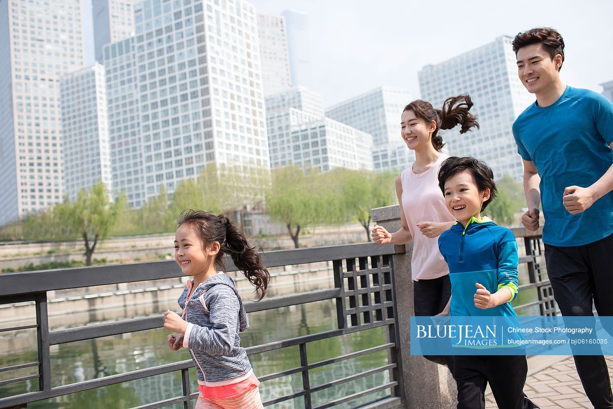 Happy young Chinese family running in park