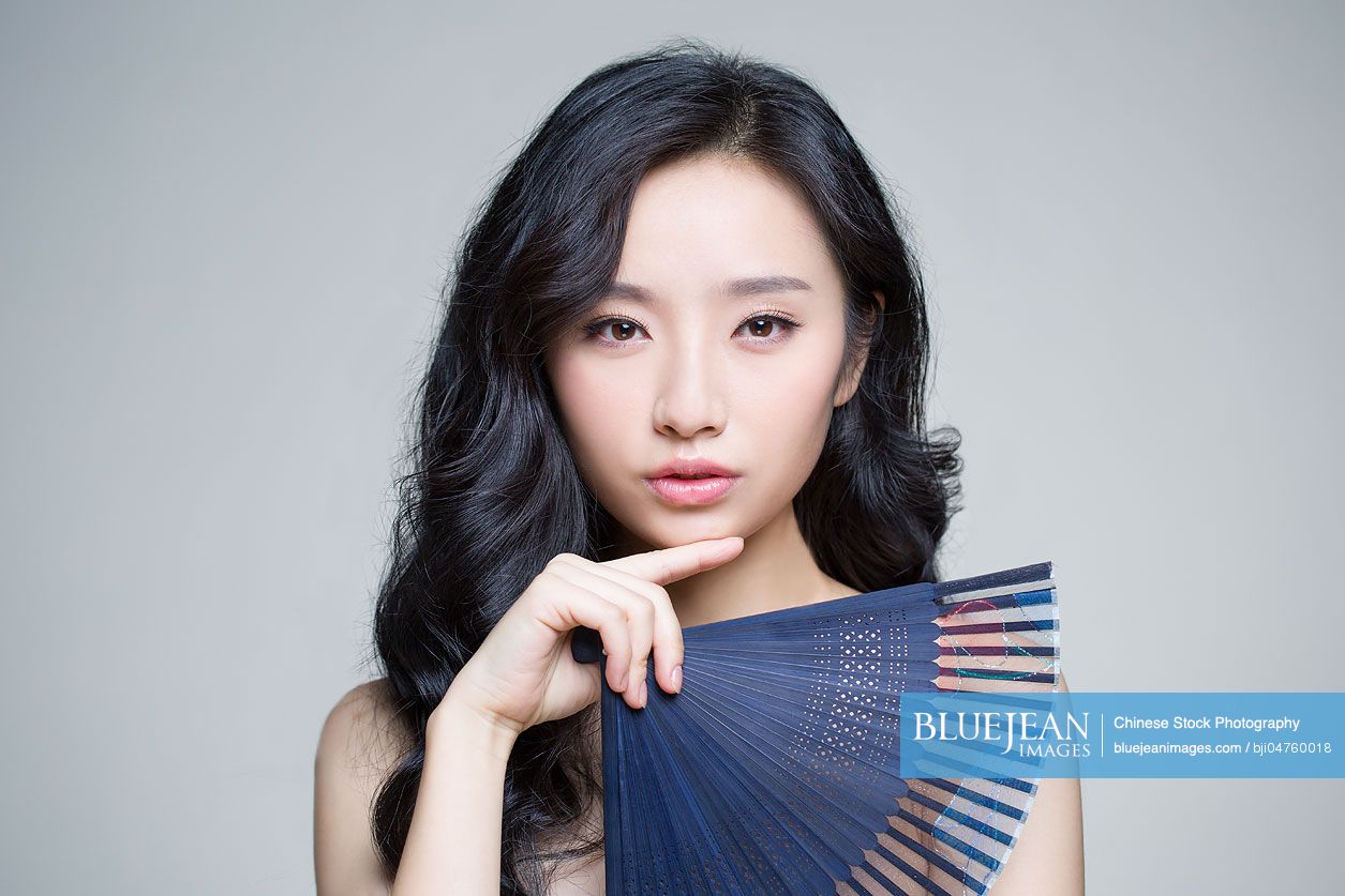 Beautiful young Chinese woman with folding fan