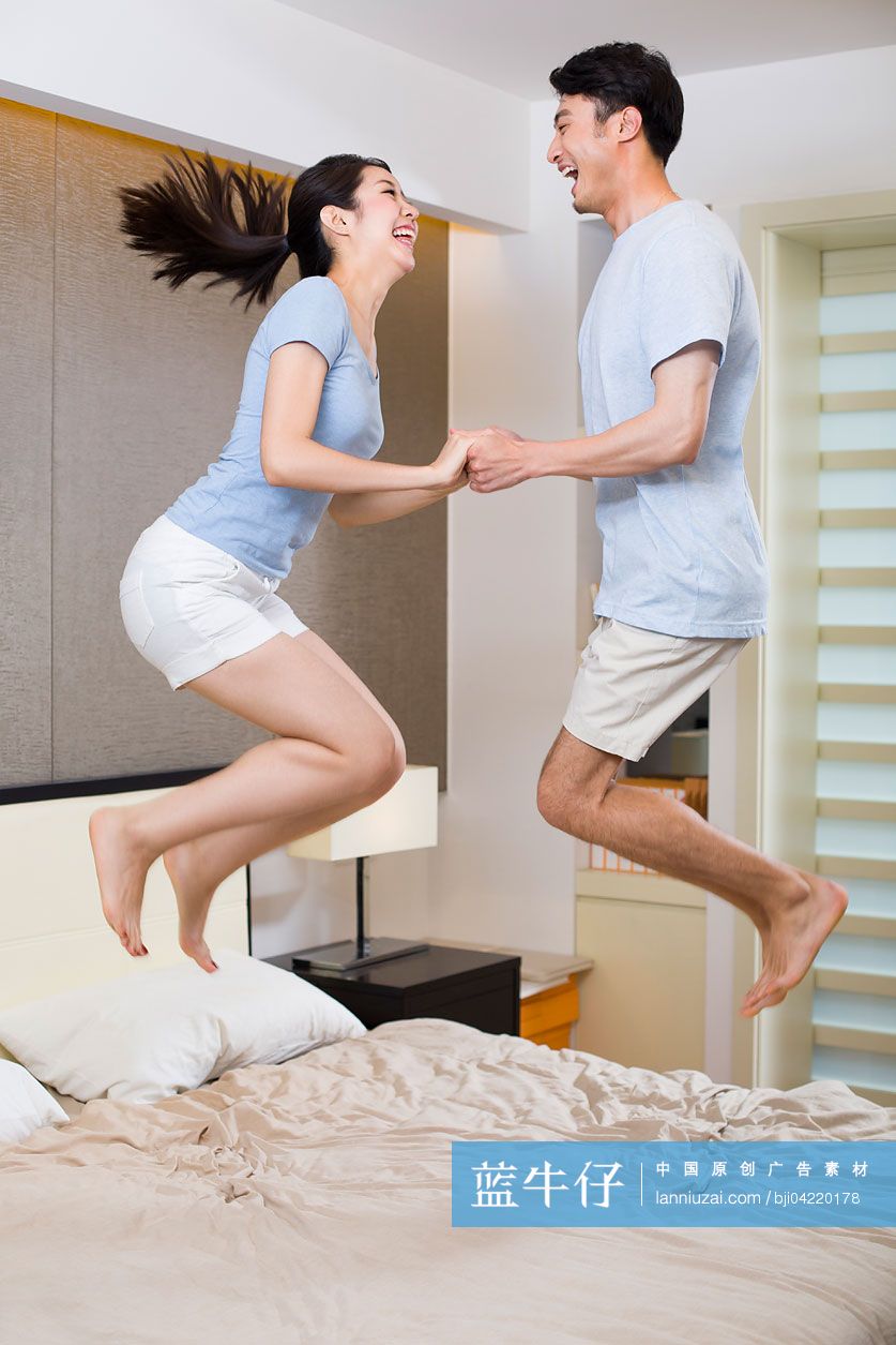年轻夫妇在床上跳跃