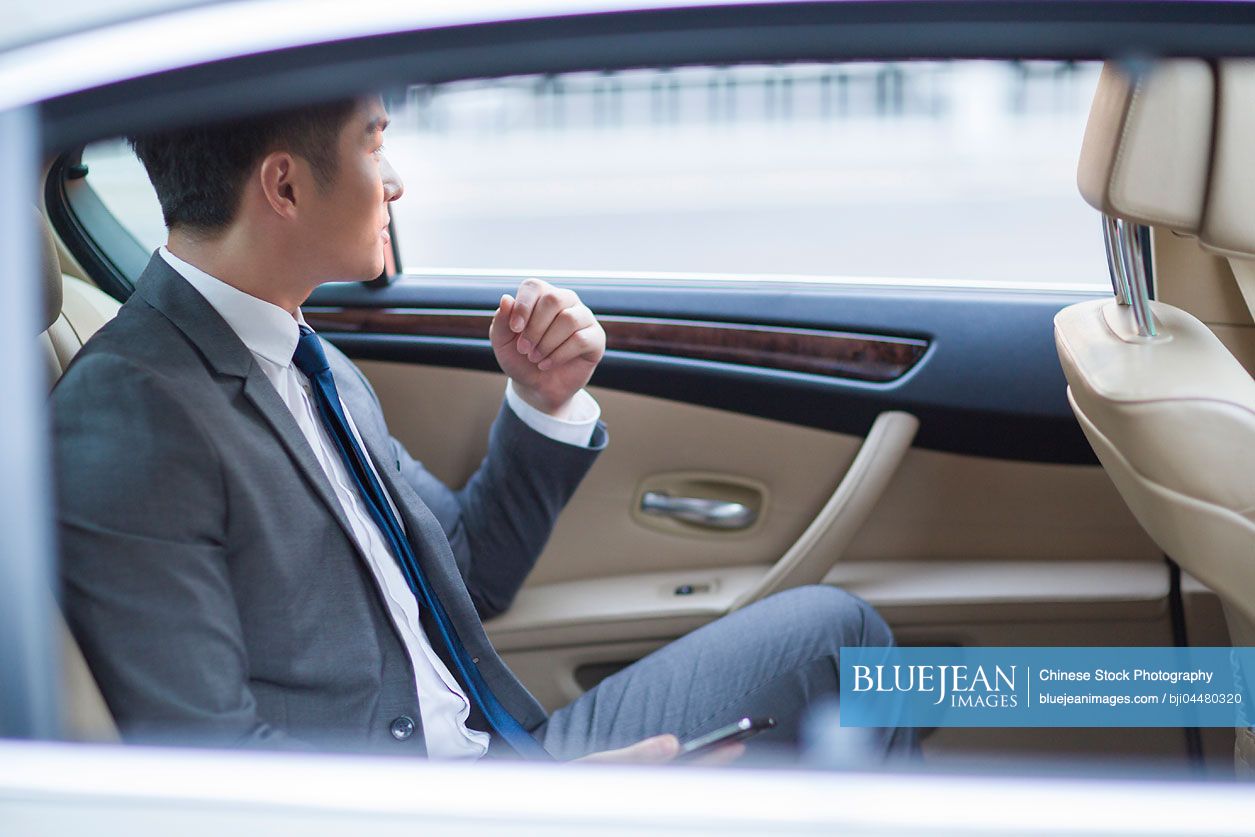 Chinese businessman sitting in car back seat