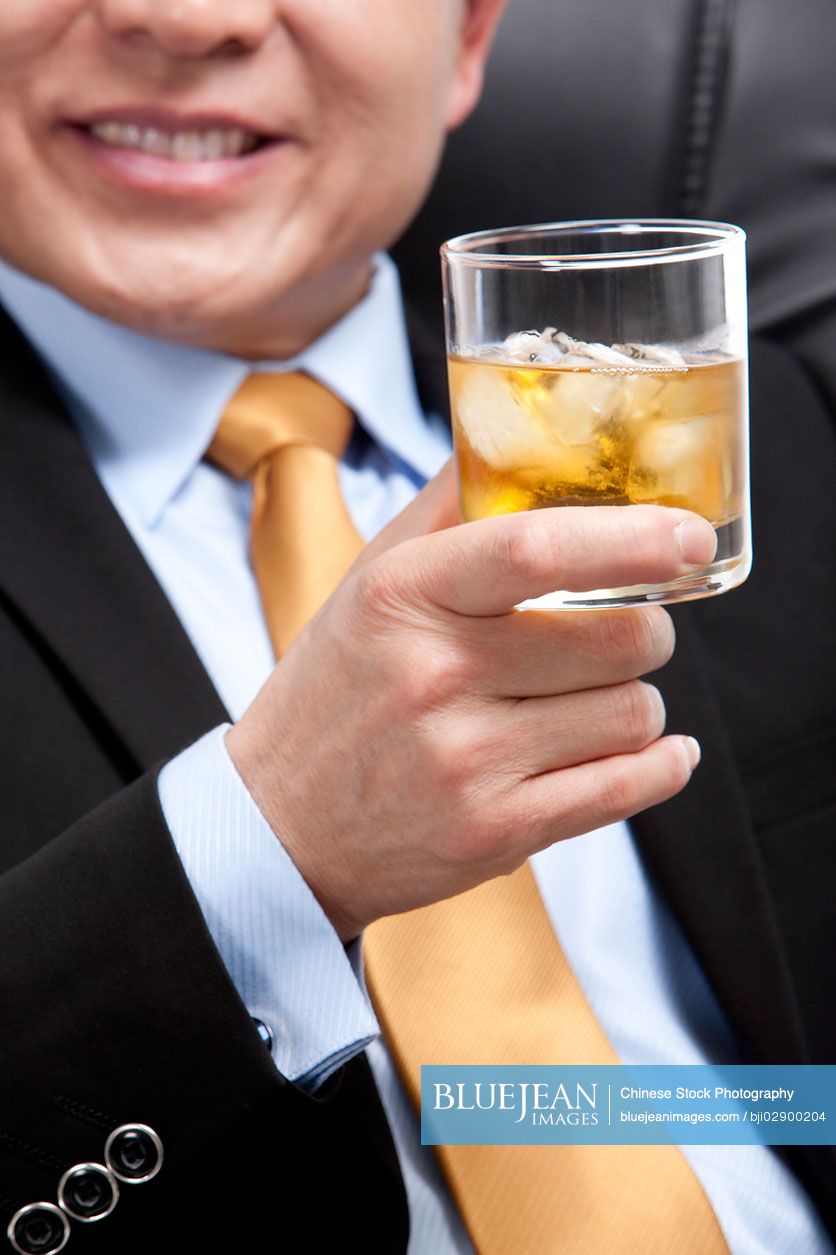 Chinese businessman holding a glass of whiskey