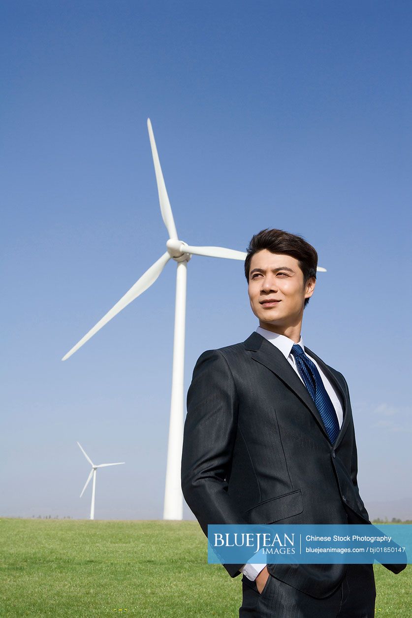 Chinese businessman in front of wind turbine