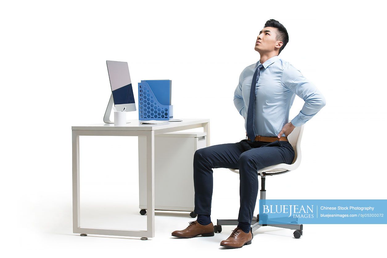 Young Chinese businessman exercising in office