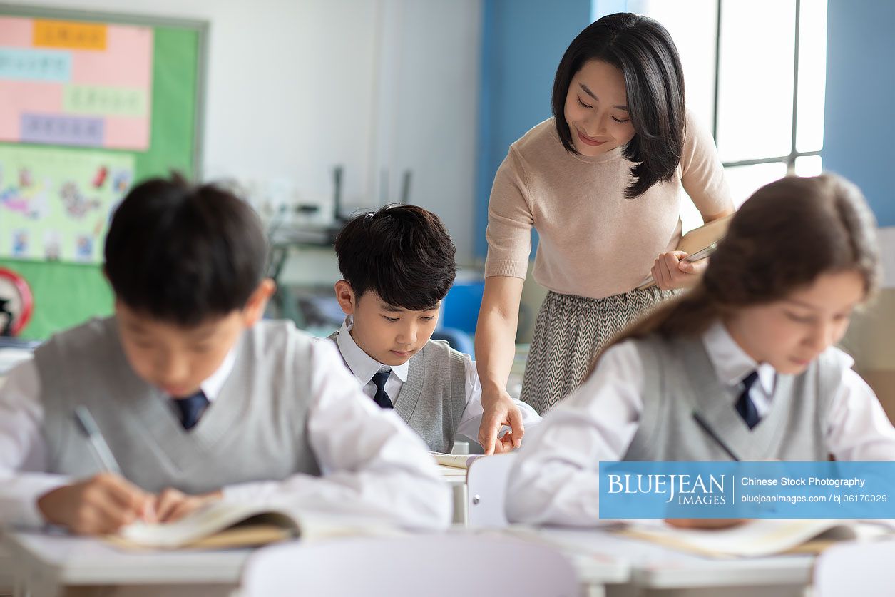 Young Chinese teacher helping students in classroom-High-res stock ...
