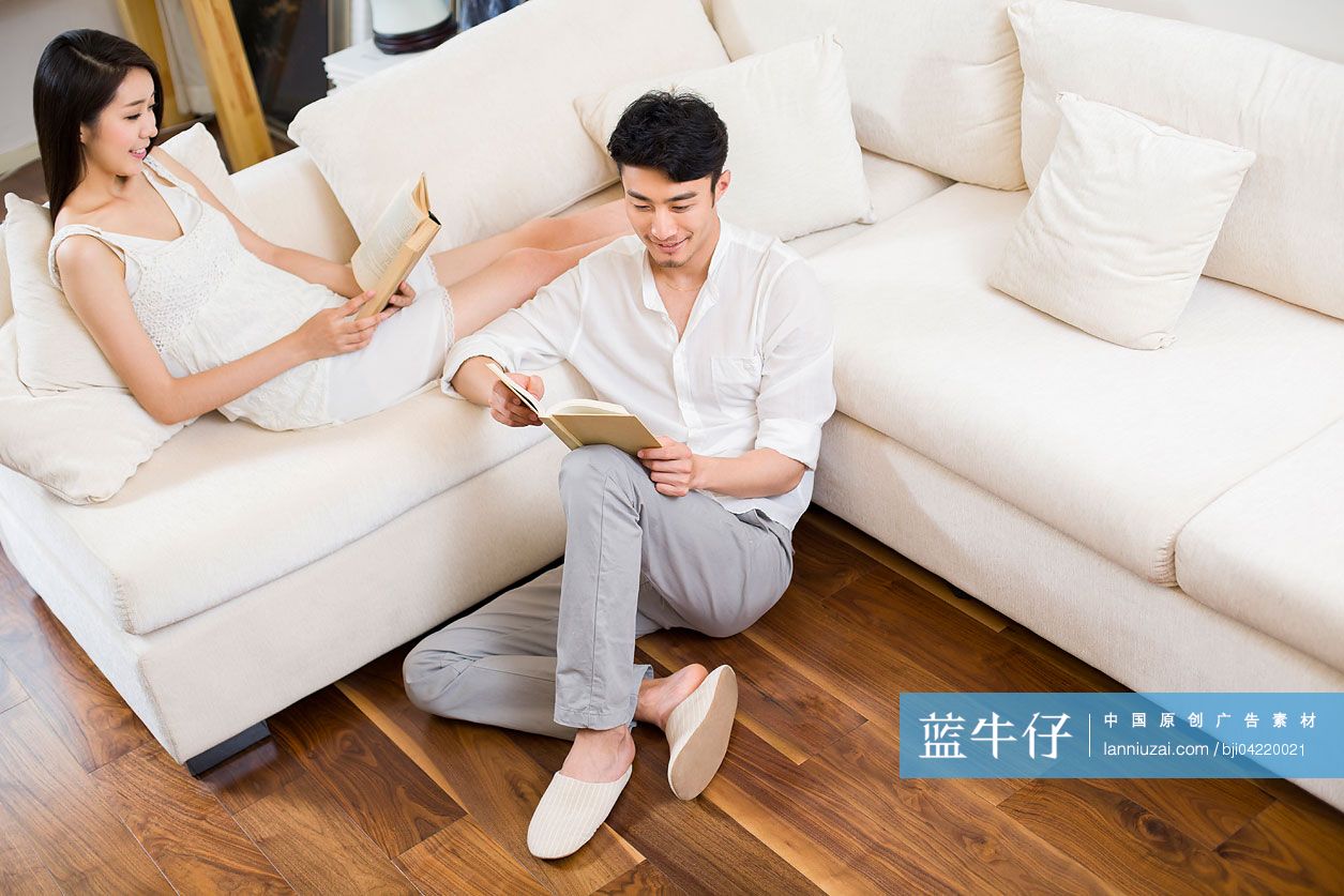 快乐的年轻情侣在客厅看书