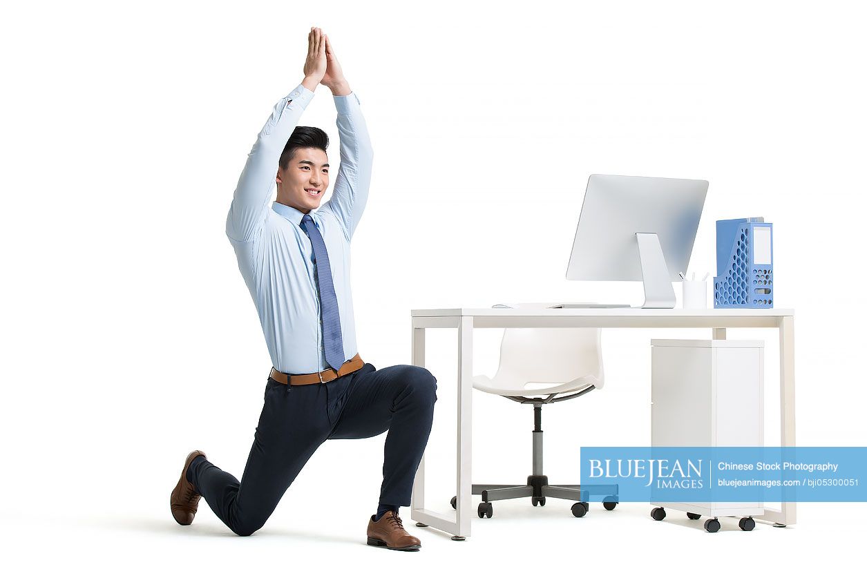 Young Chinese businessman exercising in office