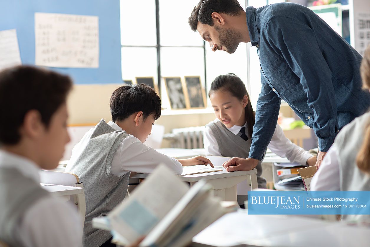 Young teacher helping students in classroom