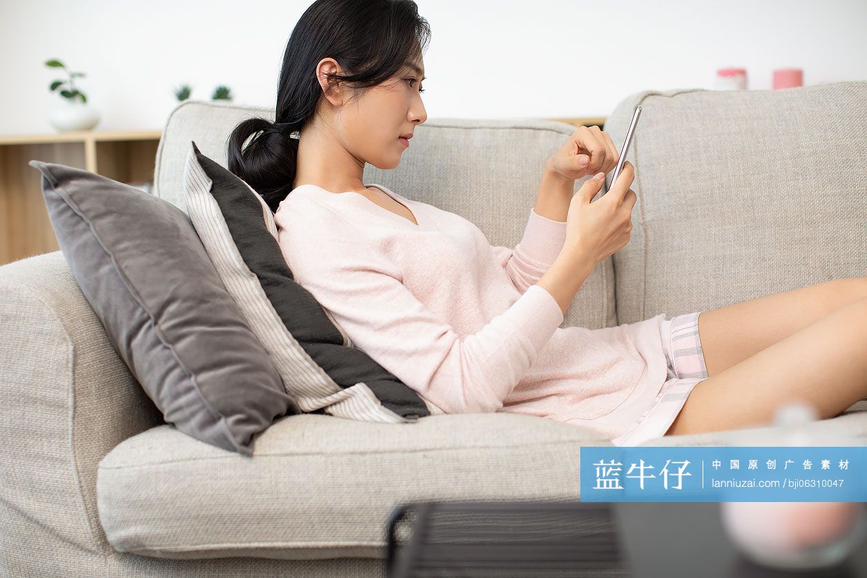 年轻女士在沙发上使用手机