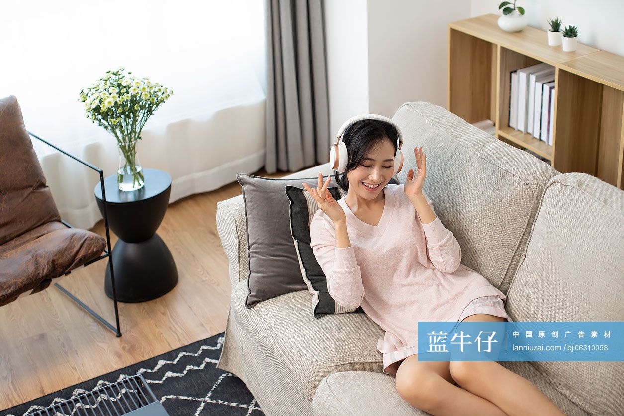 快乐年轻女士在家戴着耳机听音乐