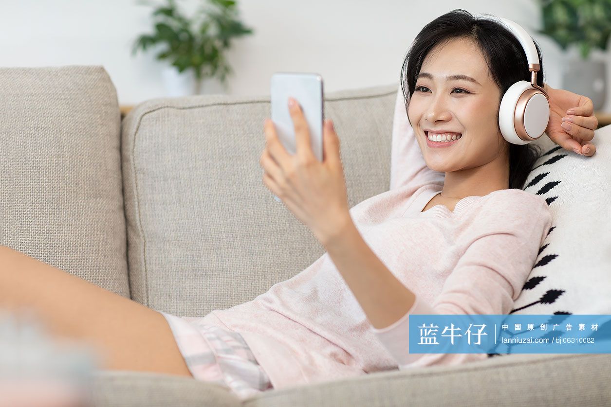 快乐年轻女士在家戴着耳机听音乐