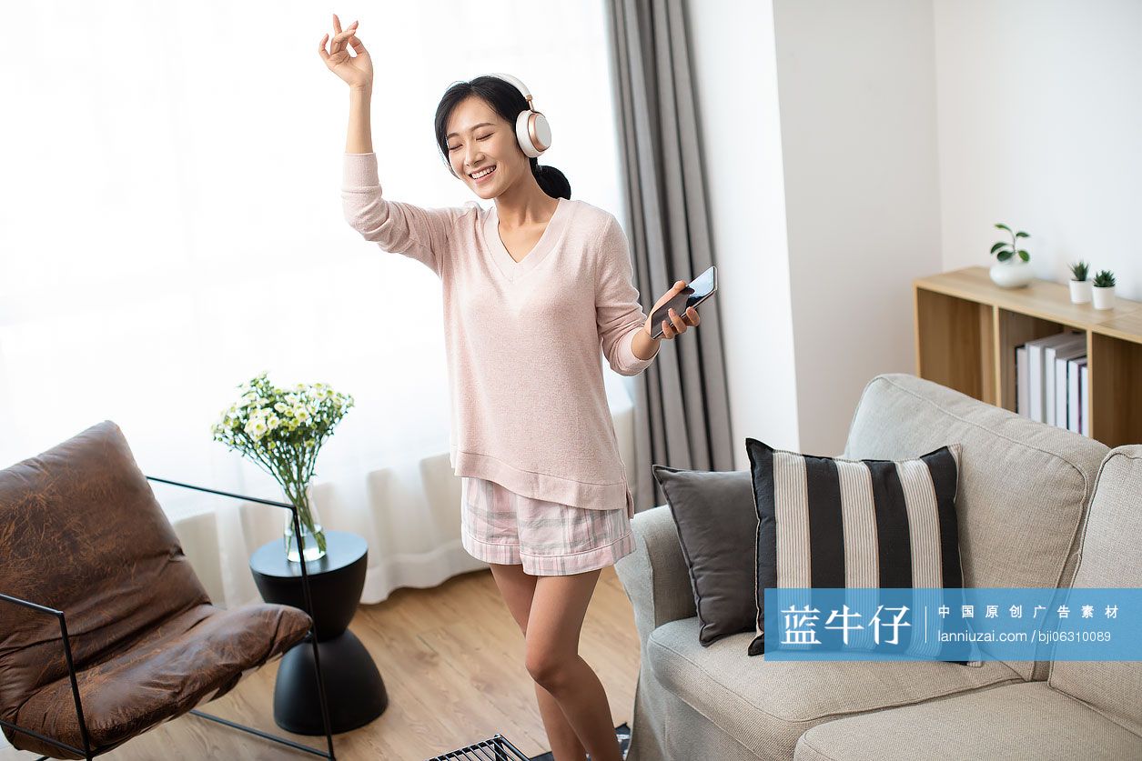 快乐年轻女士在家戴着耳机听音乐