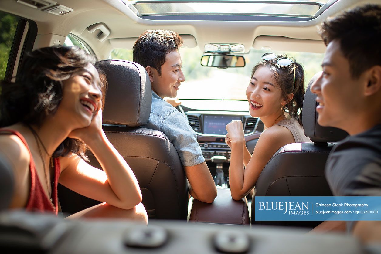 Happy young Chinese friends enjoying road trip