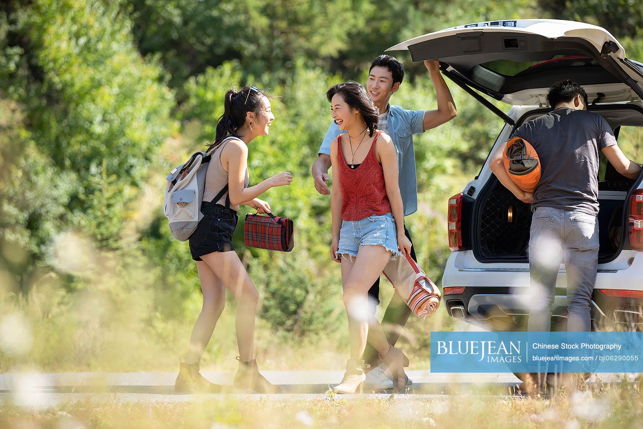 Happy young Chinese friends camping outdoors