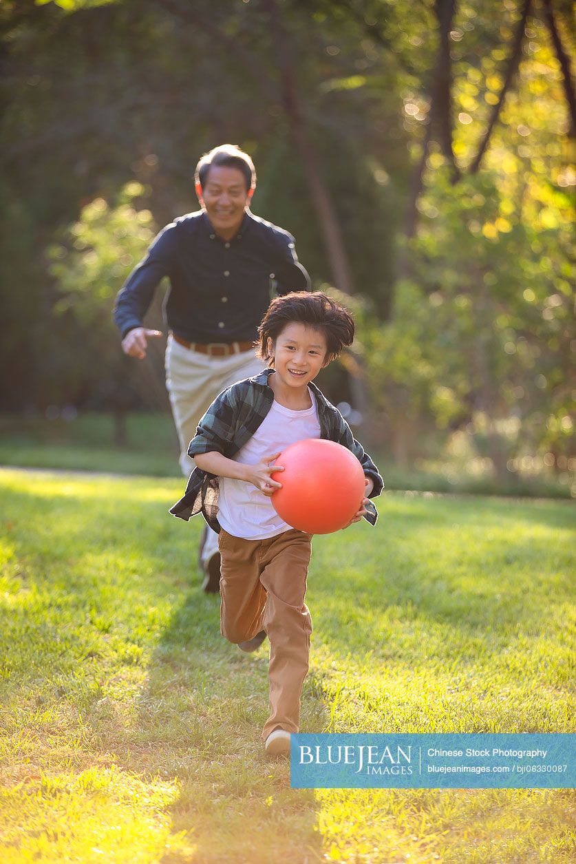 Happy Chinese grandfather and grandson having fun in park
