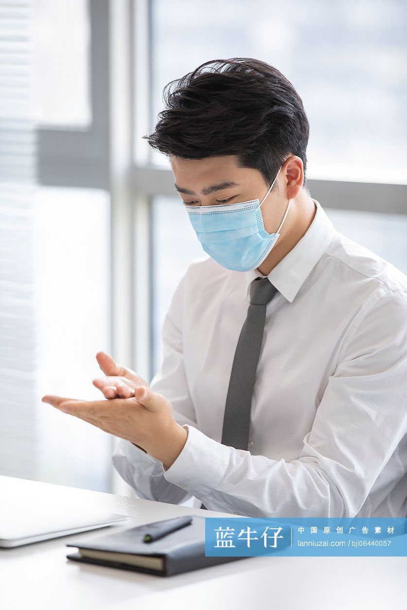 年轻的商务男士在办公室使用免洗洗手液