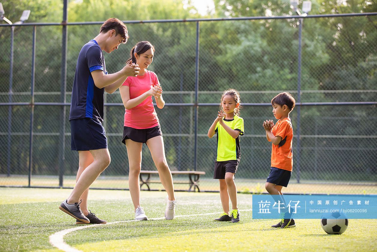 快乐的年轻家庭在足球场热身