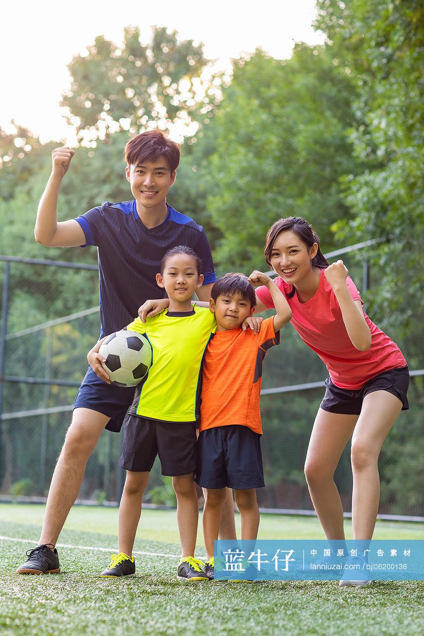 快乐的年轻家庭在足球场踢足球