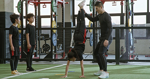 Active Chinese children having exercise class with their coach in gym,4K