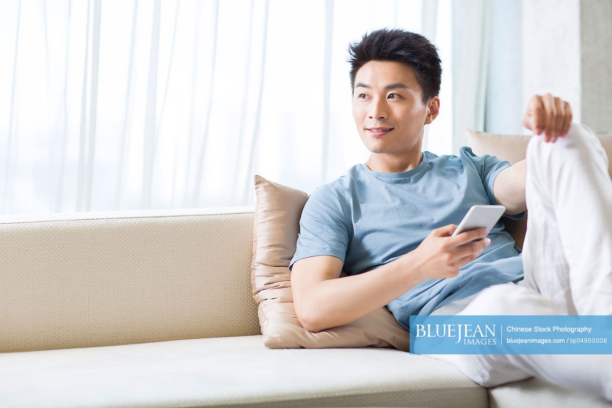 young-chinese-man-relaxing-on-the-sofa-high-res-stock-photo-for-download