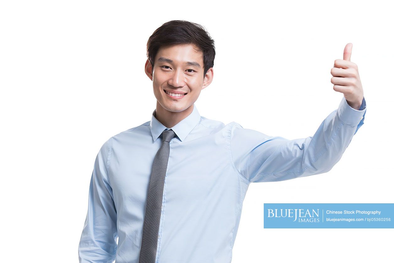 Confident young Chinese businessman doing thumbs-up