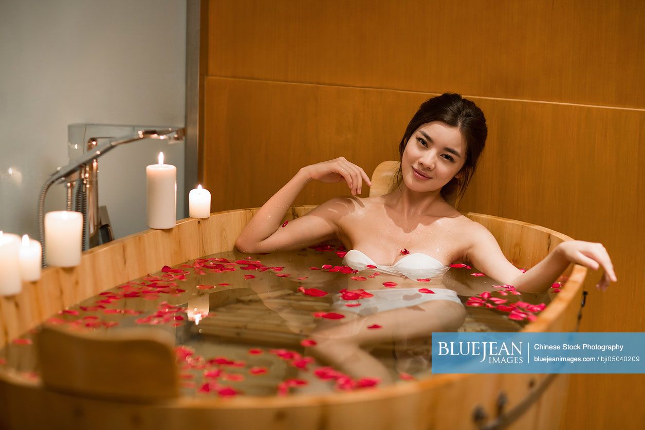Beautiful young Chinese woman in bathtub with rose petals