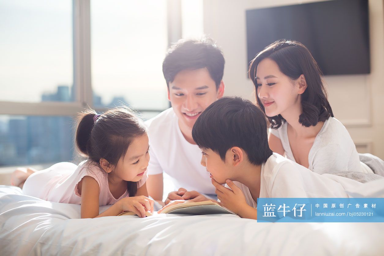 快乐的年轻家庭在床上看书