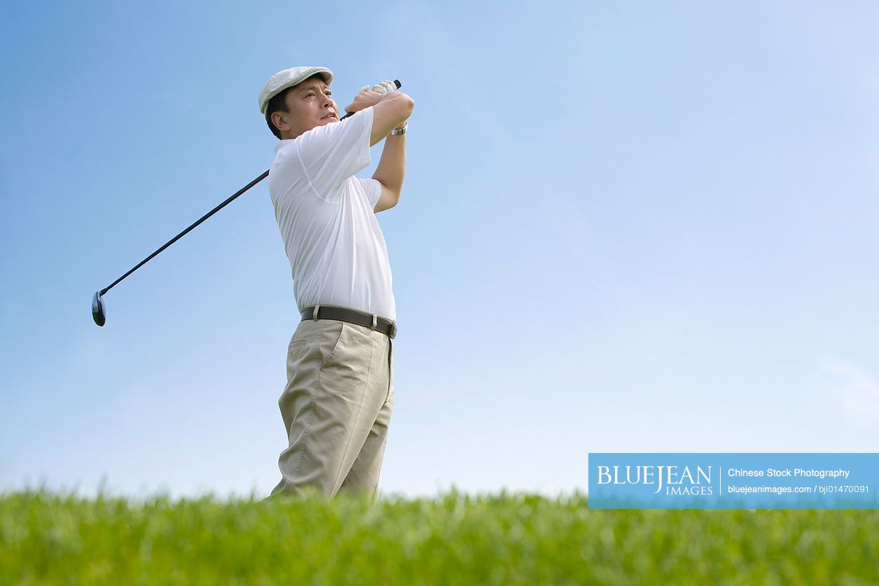 Male Chinese golfer swinging club