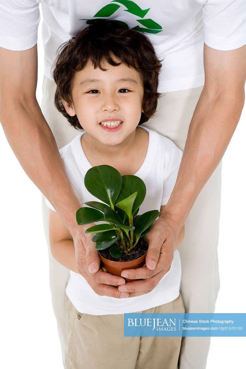 Little Chinese boy holding a potted plant