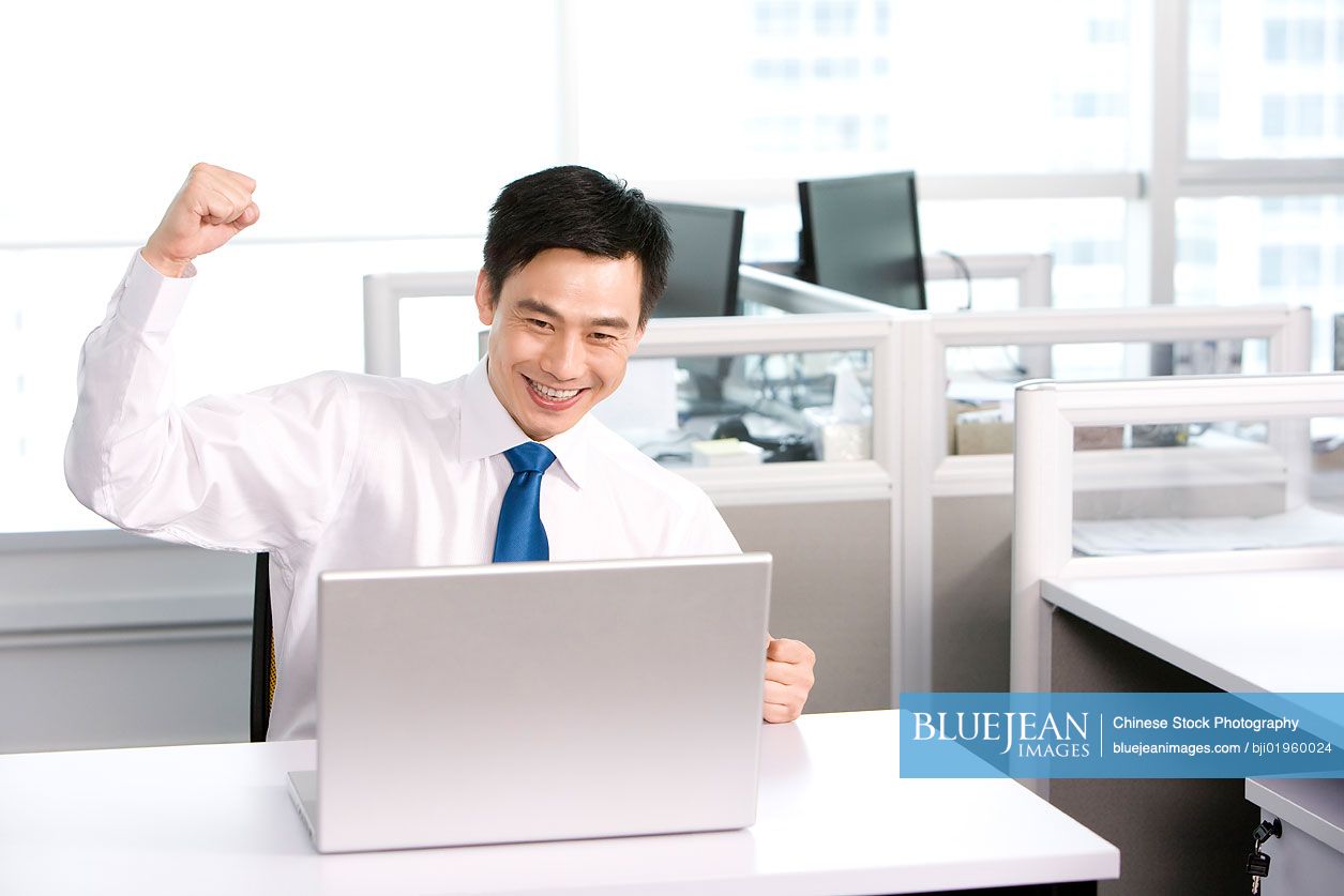 Happy Chinese office worker at his desk
