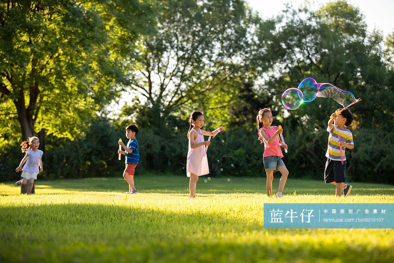 快乐的儿童在草地上吹泡泡