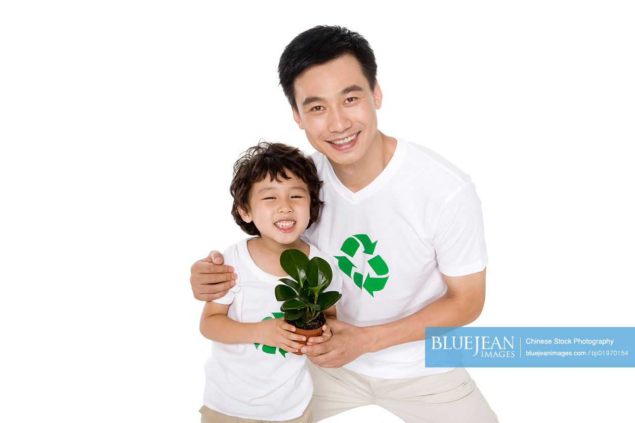 Little Chinese boy with his father holding a potted plant