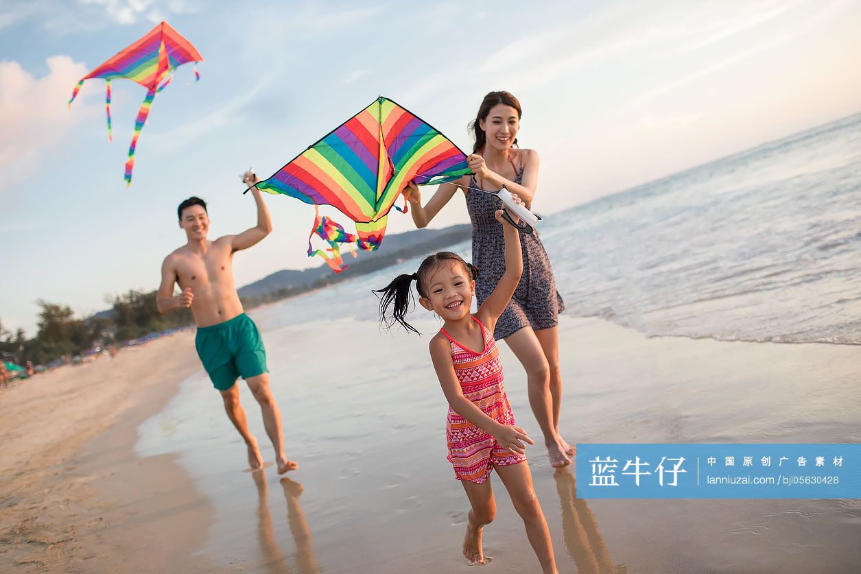 快乐的年轻家庭在沙滩放风筝