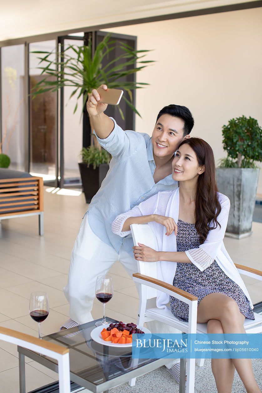 Happy young Chinese couple taking selfie with smartphone