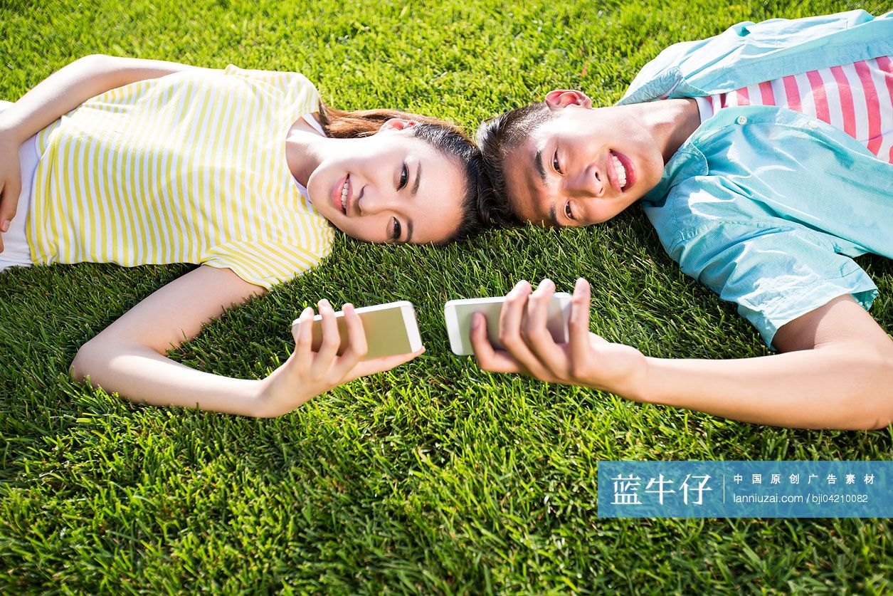 情侣躺在草地上玩手机