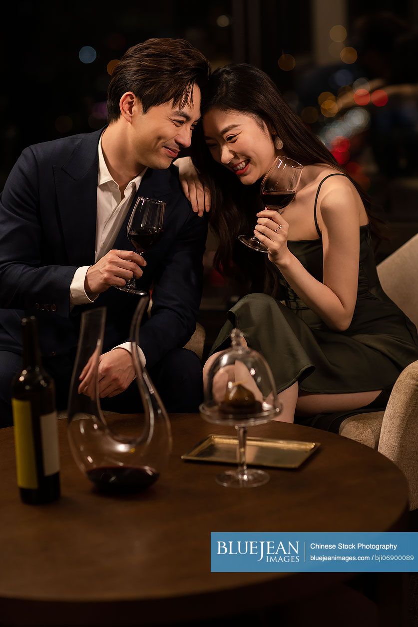 Elegant young Chinese couple enjoying red wine