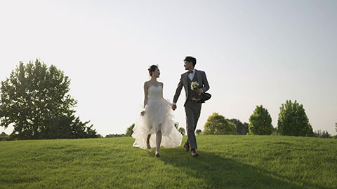 Happy bride and groom running on grass