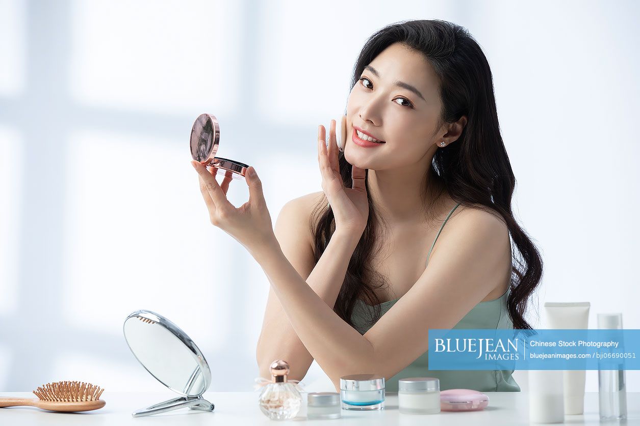 Young beautiful Chinese woman putting on make up