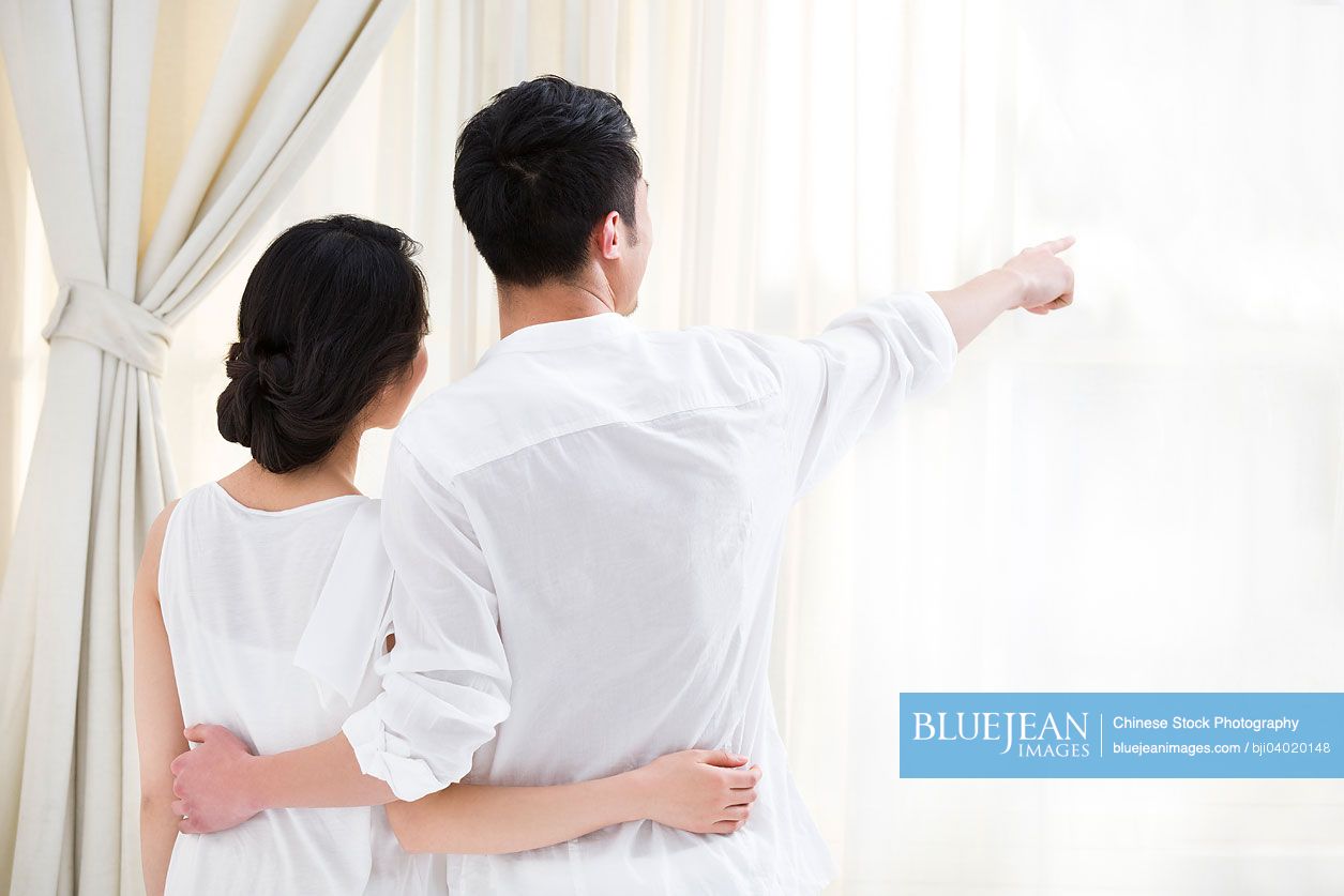 Happy young Chinese couple looking out of window