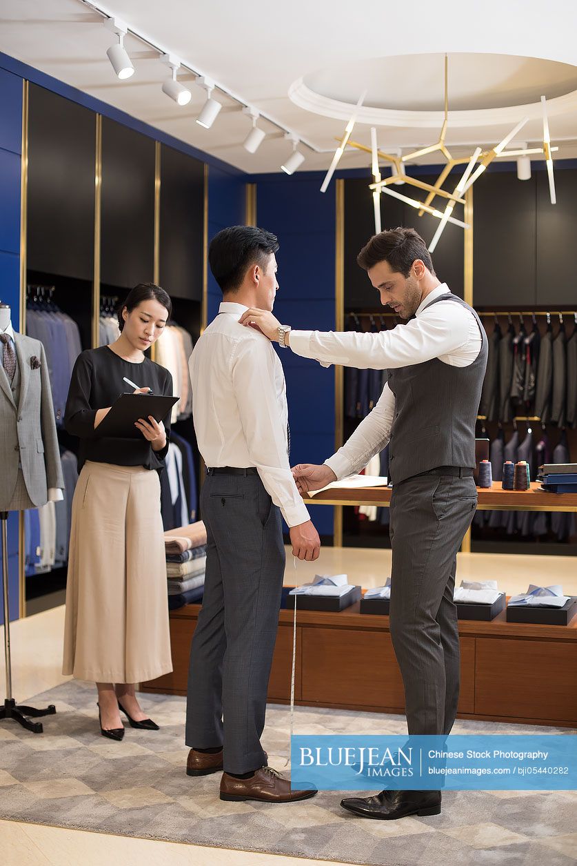 Chinese fashion designers taking measurement of customer