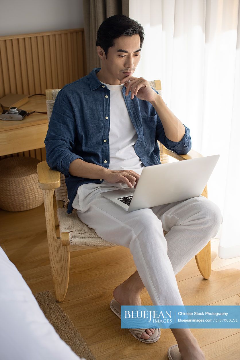 Mid adult Chinese man using laptop at home