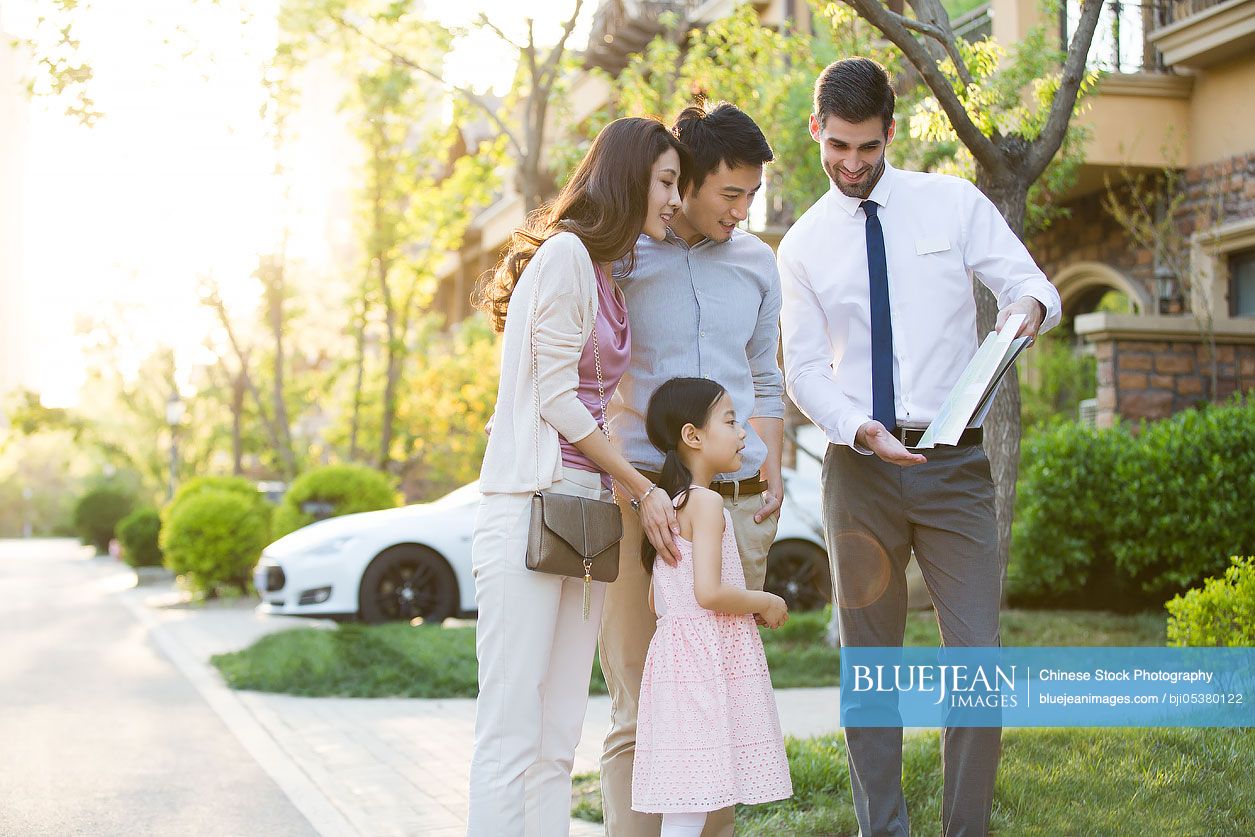 Happy young Chinese family and real estate agent