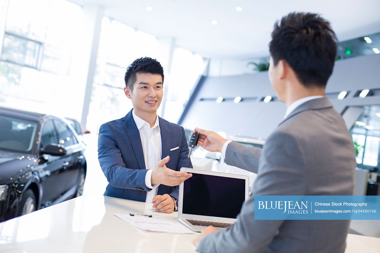 Young Chinese man buying car in showroom