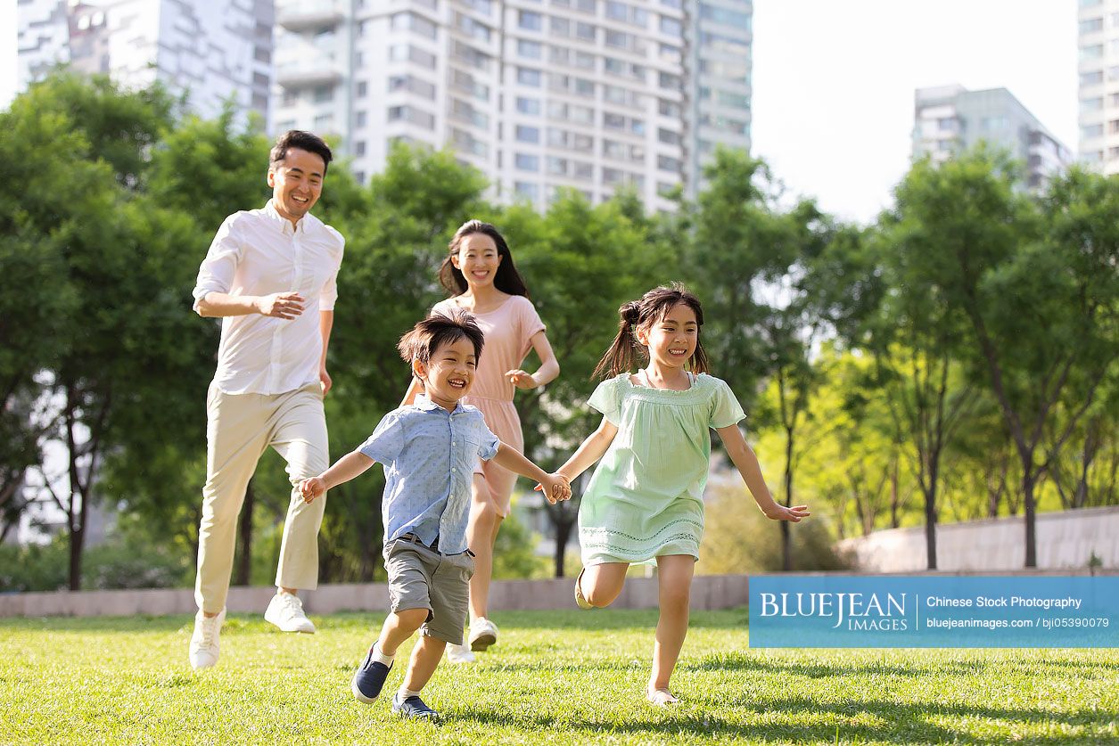 Happy young Chinese family playing in park