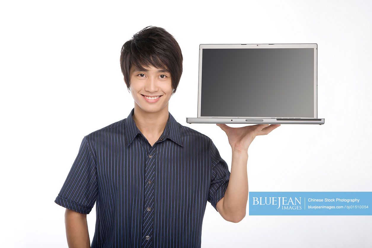 Young Chinese man holding laptop in hand