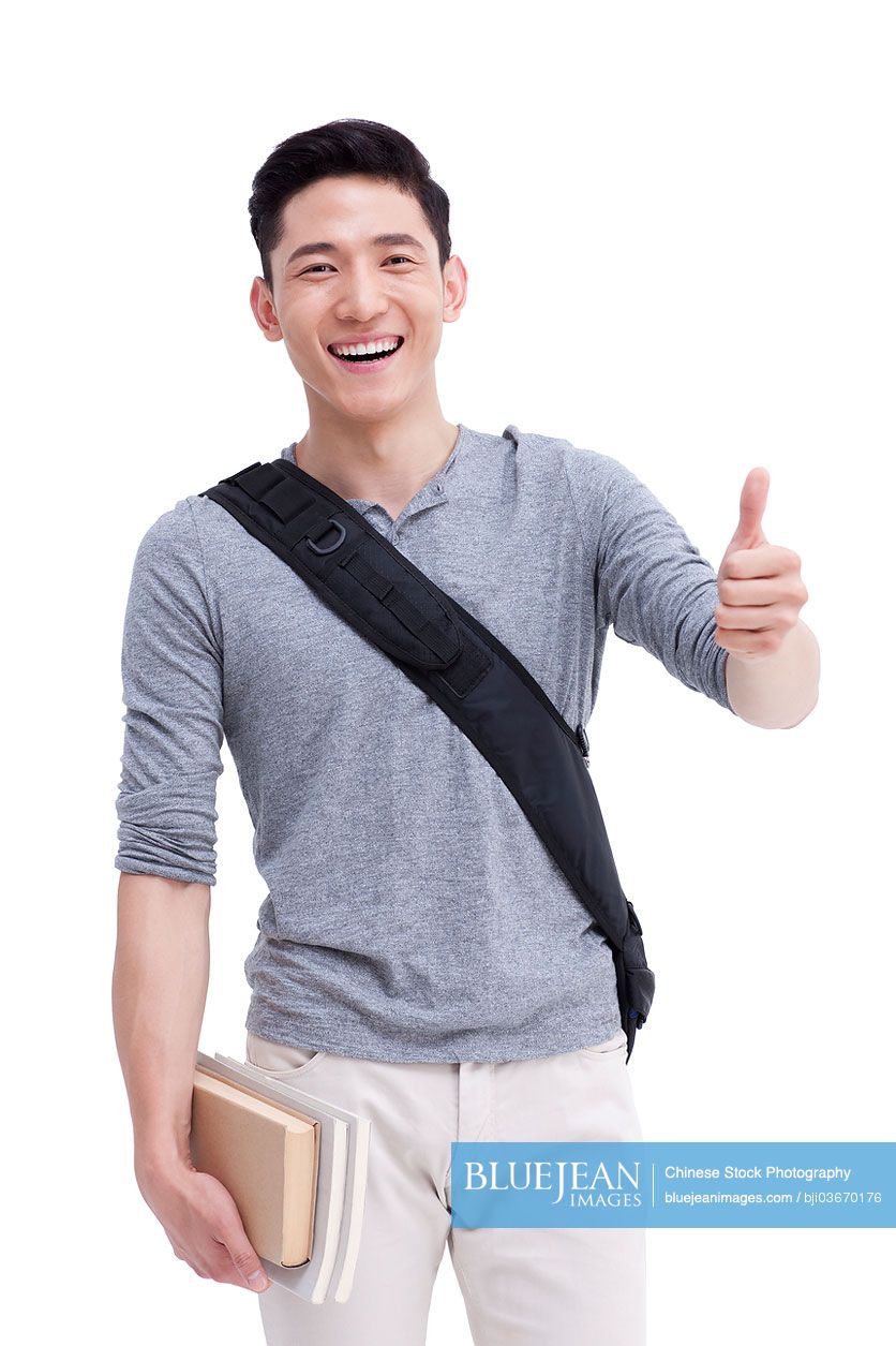 Cheerful male Chinese college student doing thumbs up