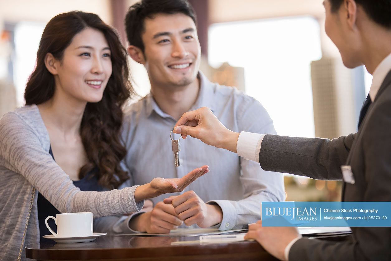Happy young Chinese couple buying new house from realtor